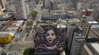 Sebuah mural raksasa karya seniman yang dikenal sebagai BIP, dipajang di dinding bangunan di Sao Paulo, Brasil, Rabu (29/9/2021). Para seniman mural papan atas dikerahkan membuat lukisan raksasa karya terbaik mereka untuk berpartisipasi dalam festival selama seminggu. (AP Photo/Andre Penner)