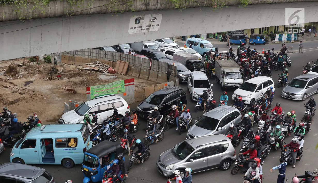 Petugas Dishub mengatur arus lalu lintas di Simpang Matraman, Jakarta, Rabu (19/7). Rekayasa lalu lintas terkait pembangunan simpang tidak sebidang atau underpass di kawasan tersebut akan diuji coba pada 20-27 Juli. (Liputan6.com/Immanuel Antonius)
