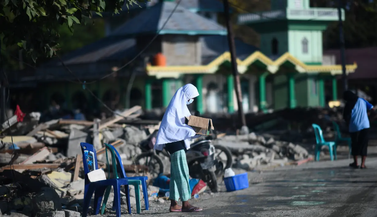 Seorang anak yang terkena dampak gempa meminta sumbangan pada pengguna jalan yang melintas di Donggala, Sulawesi Tengah, Jumat (5/10). Akibat terlambatnya pasokan bantuan, mereka terpaksa meminta sumbangan hingga turun ke jalan. (AFP PHOTO / Jewel SAMAD)