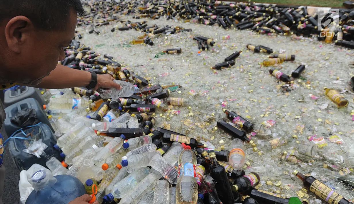Petugas membuang minuman keras (miras) hasil sitaan saat pemusnahan di halaman Polres Bogor, Cibinong, Kamis (17/5). Miras yang dimusnahkan lebih dari 32 ribu botol, baik lokal maupun impor dengan beragam merek. (Merdeka.com/Arie Basuki)