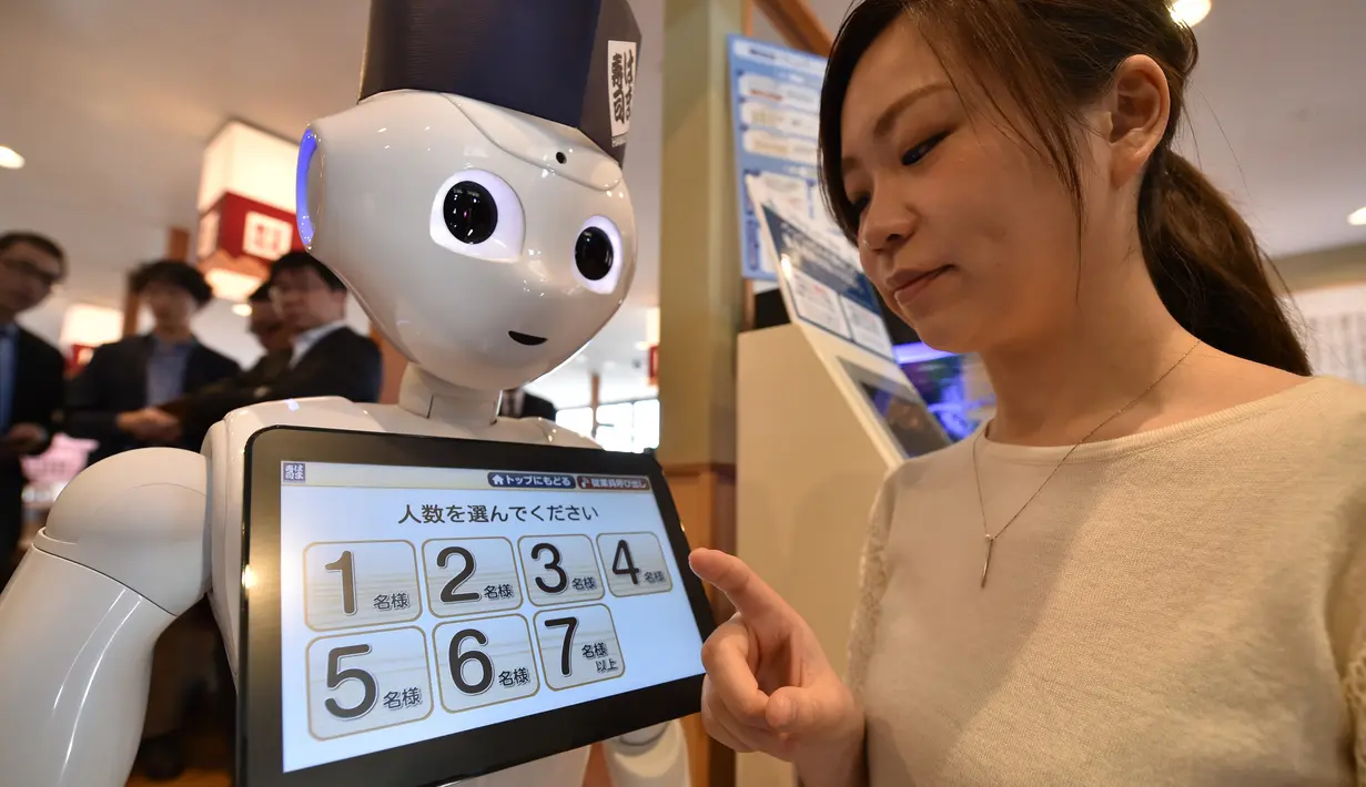 Seorang karyawati dari restoran sushi Hamazushi menguji coba robot humanoid Pepper saat press preview di Saitama, Jepang (2/2). Robot tersebut dapat melayani pelanggan dan membuka pintu masuk ke meja resepsionis. (AFP/Kazuhiro Nogi)
