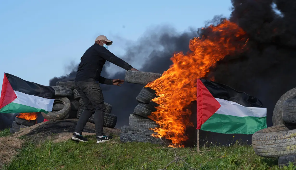 Seorang demonstran membakar ban saat protes terhadap serangan militer Israel ke Kota Nablus, Tepi Barat, di sepanjang pagar perbatasan dengan Israel di sebelah timur Kota Gaza, 22 Februari 2023. Para pejabat Palestina mengatakan sejumlah warga Palestina telah terbunuh dan lebih dari seratus orang terluka dalam serangan tentara Israel yang jarang terjadi di Tepi Barat. (AP Photo/Adel Hana)
