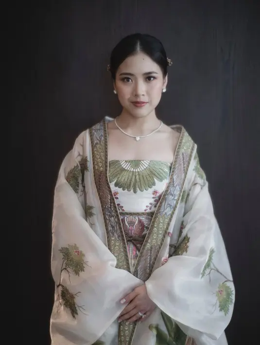 Jessica Tanoesoedibjo mengenakan cheongsam nuansa putih kehijauan dengan detail motif Cendrawasih yang melambangkan bird of paradise, serta motif flora dan fauna saat tea pai. [Instagram].