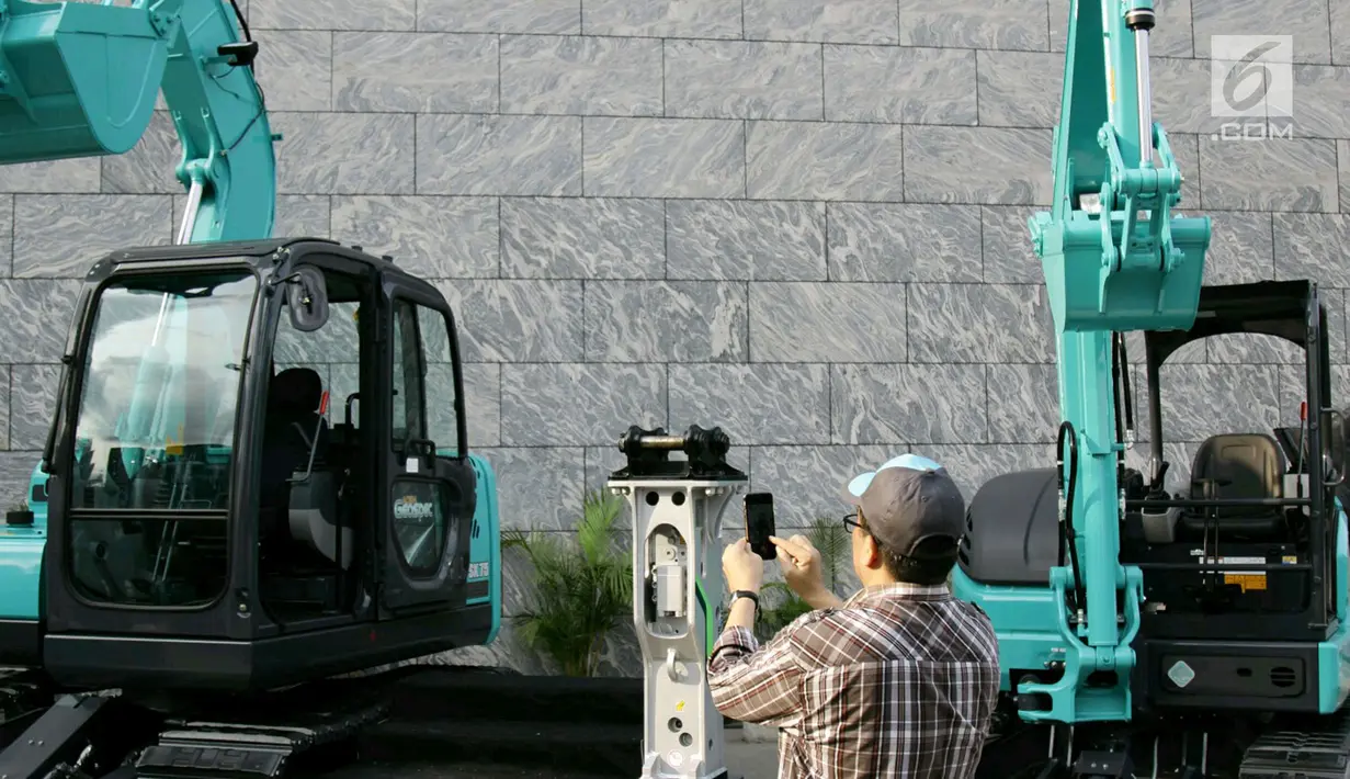 Pengunjung mengambil gambar alat berat yang dipajang dari produk Kobelco di Jakarta, Jumat (15/2). Pameran ini bertujuan untuk memenuhi kebutuhan sektor kehutanan, pertanian, pertambangan dan konstruksi di Indonesia. (Liputan6.com/Faizal Fanani)