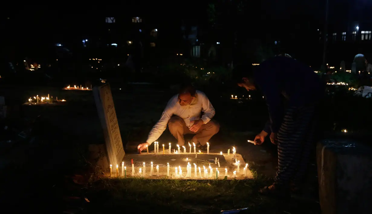 Seorang pria menyalakan lilin di pemakaman keluarga dan saudara mereka saat memperingati Shab-e-Barat di pinggiran Srinagar, Kashmir (11/5). Selain itu mereka juga berdoa untuk sanak keluarga mereka. (AP Photo / Mukhtar Khan)