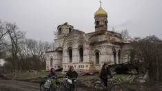 Warga berjalan dengan sepeda mereka di depan sebuah gereja yang rusak, di Lukashivka, di utara Ukraina, 22 April 2022. Penduduk mengatakan tentara Rusia menggunakan rumah ibadah untuk menyimpan amunisi, dan pasukan Ukraina menembaki gedung itu untuk membuat Rusia pergi. (AP Photo/Petros Giannakouris)