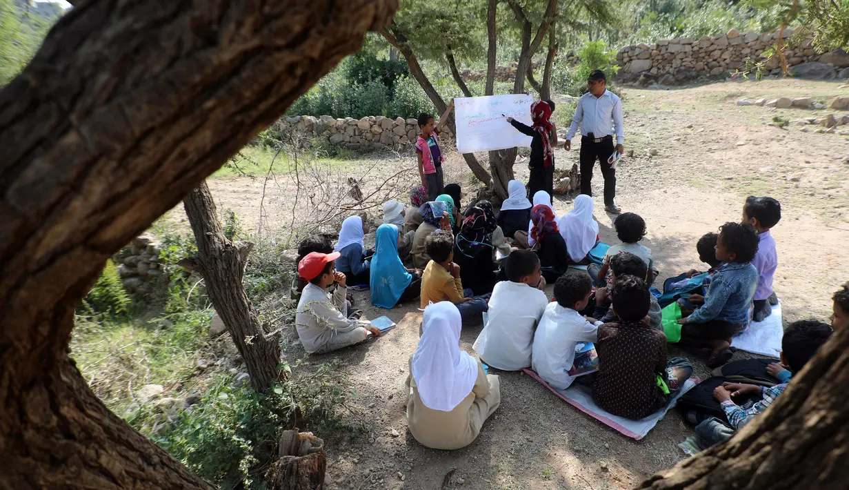 Anak-anak menghadiri kelas terbuka di bawah pohon dekat sekolah mereka yang belum selesai pada tahun ajaran baru di negara yang dilanda perang di desa al-Kashar Yaman barat daya di distrik Mashraa dan Hadnan di provinsi Taez (16/9/2019). (AFP Photo/Ahmad Al-Basha)