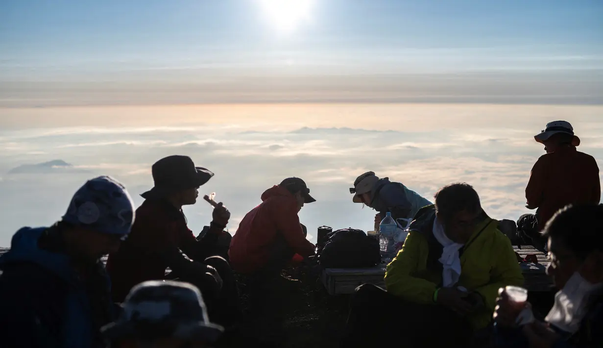 Orang-orang sarapan setelah menyaksikan matahari terbit dari puncak Gunung Fuji, barat Tokyo pada 19 Juli 2021. Mendaki Gunung Fuji bukan hal yang mudah, tetapi pemandangan matahari terbit di atas lautan awan adalah hadiah indah bagi yang mencapai puncak tertinggi di Jepang. (Charly TRIBALLEAU/AFP)