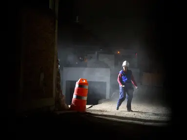 Seorang petugas penyelamat berjalan disamping bangunan garasi parkir bawah tanah yang runtuh di sebuah kompleks di Mexico City (10/4). Akibat insiden tersebut, sejumlah orang tewas dan masih terjebak di dalam. (AP Photo/Rebecca Blackwell)