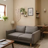 Rumah kecil dengan ruang tamu dan ruang makan menyatu sehingga terlihat elegan untuk hunian KPR dan subsidi model sofa menghadap dinding dan meja makan di belakangnya (AI generated)