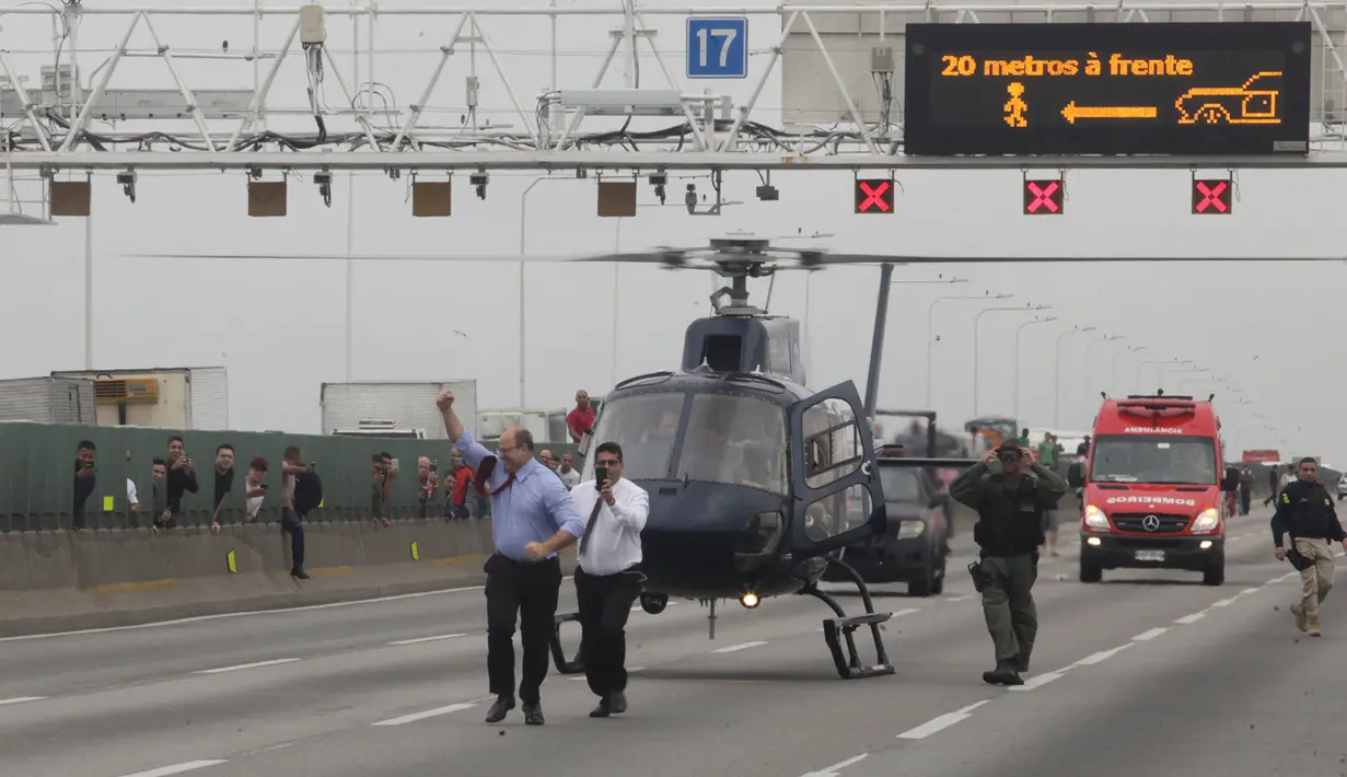 Gubernur Rio de Janeiro Wilson Witzel mengepalkan tinjunya saat tiba dengan helikopter di lokasi penyenderaan sebuah bus di jembatan yang menghubungkan Kota Niteroi dengan Rio de Janeiro, Brasil, Selasa (20/8/2019). Penyandera tidak mengajukan tuntutan khusus. (Ricardo Cassiano/Agencia O Dia via AP)