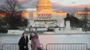 Dua orang wanita mengambil gambar dengan latar belakang Gedung Capitol, Washington DC yang merupakan tempat pelantikan Donald Trump dan Mike Pence sebagai presiden dan wakil presiden AS, Kamis (19/1). (Mario Tama/Getty Images/AFP)