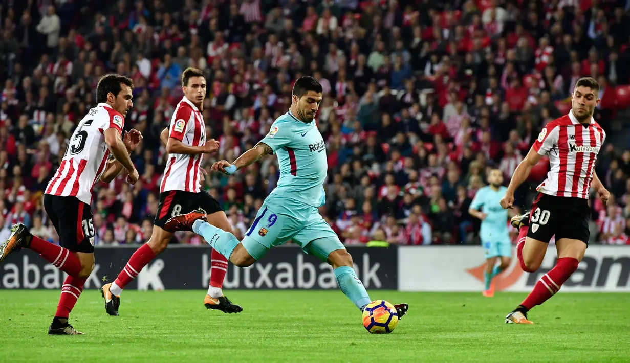 Pemain Barcelona, Luis Suarez berusaha mengontrol bola dengan kawalan pemain Athletic Bilbao pada pekan ke-10 Liga Spanyol di San Mames, Minggu (29/10) dini hari. Satu gol dari Lionel Messi dan Paulinho membawa Blaugrana menang 2-0. (AP/Alvaro Barrientos)
