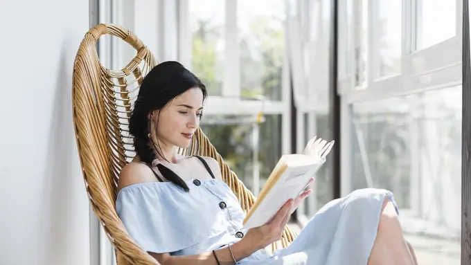 Seorang perempuan sedang membaca buku di samping jendela (Foto Dok: Freepik/freepik)