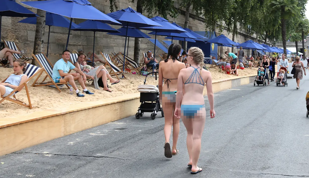 Warga berjalan dan bersantai di tepi sungai Seine pada hari pembukaan festival pantai Paris Plages, Paris, Prancis, (20/7).Festival ini untuk menyambut musim panas yang melanda Prancis.  (REUTERS / Charles Platiau)