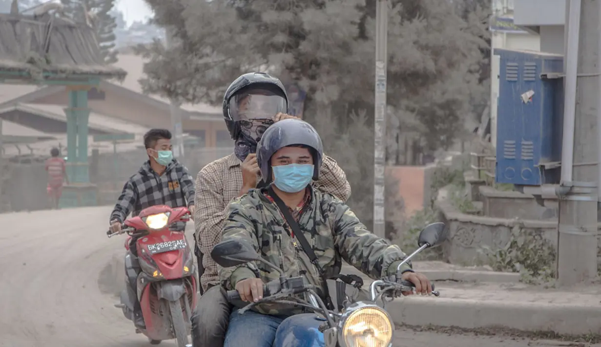 Pengendara sepeda motor memakai masker untuk mengantisipasi terhirup debu vulkanik erupsi Gunung Sinabung, di Brastagi, Karo, Sumut, Jumat (10/10). (ANTARA FOTO/Endro Lewa)
