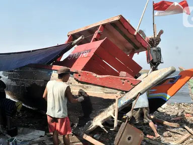 Pekerja menyelesaikan proses perbaikan kapal nelayan di pesisir Marunda, Jakarta, Selasa (22/10/2019). Jasa perbaikan kapal nelayan merupakan salah satu mata pencaharian utama warga pesisir Marunda selain mencari ikan di laut. (merdeka.com/Iqbal Nugroho)