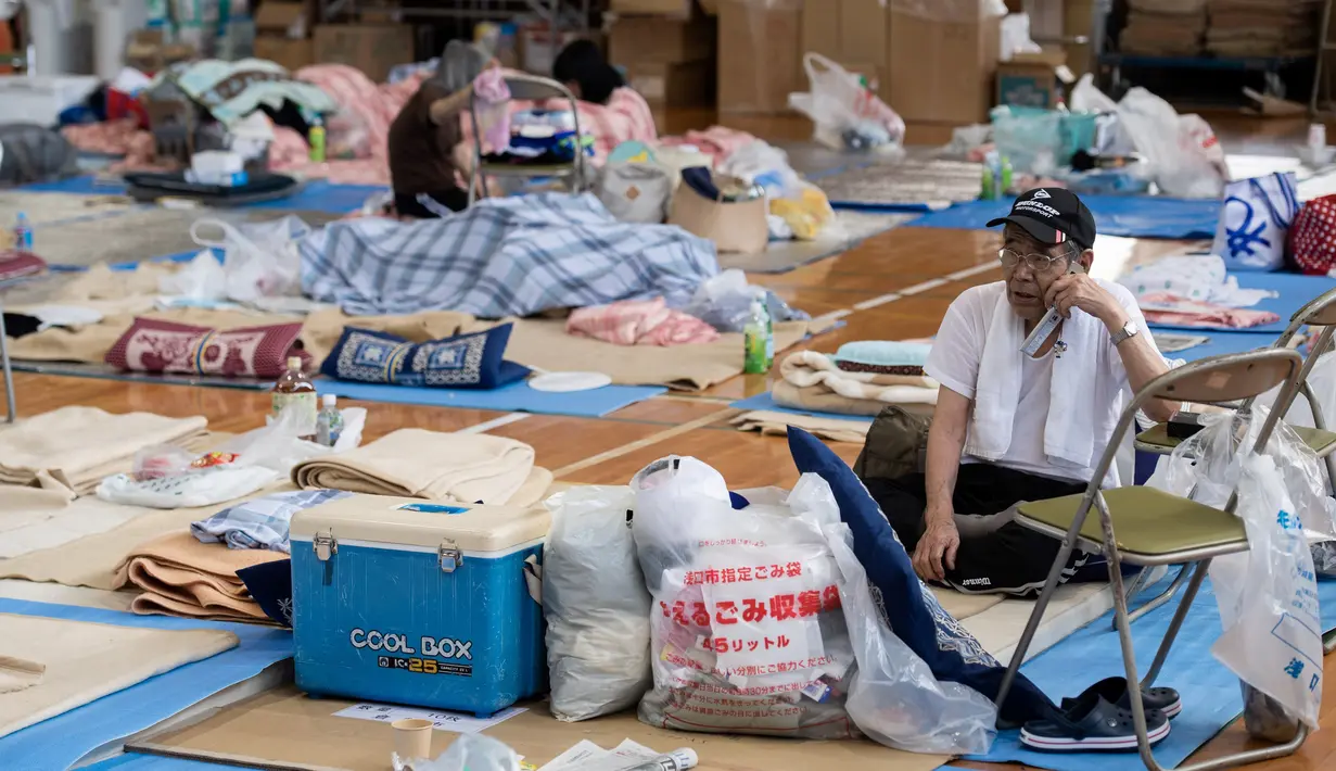 Seorang pengungsi sedang menelepon di lokasi pengungsian di Mabi, Prefektur Okayama, Jepang, Rabu (11/7). Pemerintah Jepang menyatakan banjir disertai tanah longsor telah menewaskan 179 orang. (Martin BUREAU/AFP)
