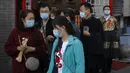 Seorang pekerja mengenakan masker untuk mencegah penyebaran virus corona berdiri menyaksikan turis bertopeng berjalan di dekat toko suvenirnya di Beijing (25/10/2020). (AP Photo/Andy Wong)