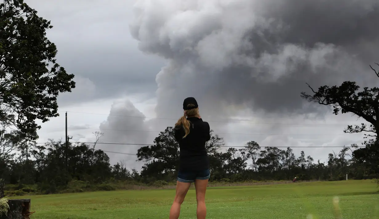 Marie Brant, dari California, menyaksikan asap tebal yang berembus dari puncak gunung berapi Kilauea di Hawaii. Kamis (17/5). Para wisatawan tetap santai dan justru menjadikan letusan gunung ini sebagai objek wisata. (AP Photo/Caleb Jones)