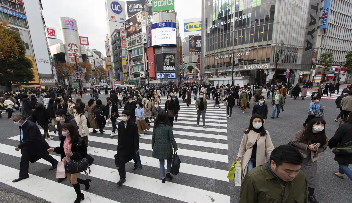 Orang-orang yang memakai masker wajah untuk membantu mengekang penyebaran Covid-19 berjalan melintasi persimpangan di Tokyo (11/12/2020). Tokyo melaporkan 621 kasus COVID-19 baru pada hari Sabtu, 12 Desember, menetapkan level tertinggi baru di ibu kota Jepang. (AP Photo / Hiro Komae)
