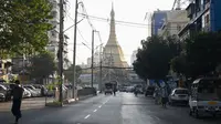 Orang-orang berjalan di sebelah Pagoda Shwedagon di jalan kosong di Yangon, Myanmar pada Senin (1/2/2021). Militer Myanmar mengumumkan satu tahun pemberlakuan situasi darurat setelah militer mengkudeta kekuasaan sipil. (STR/AFP)