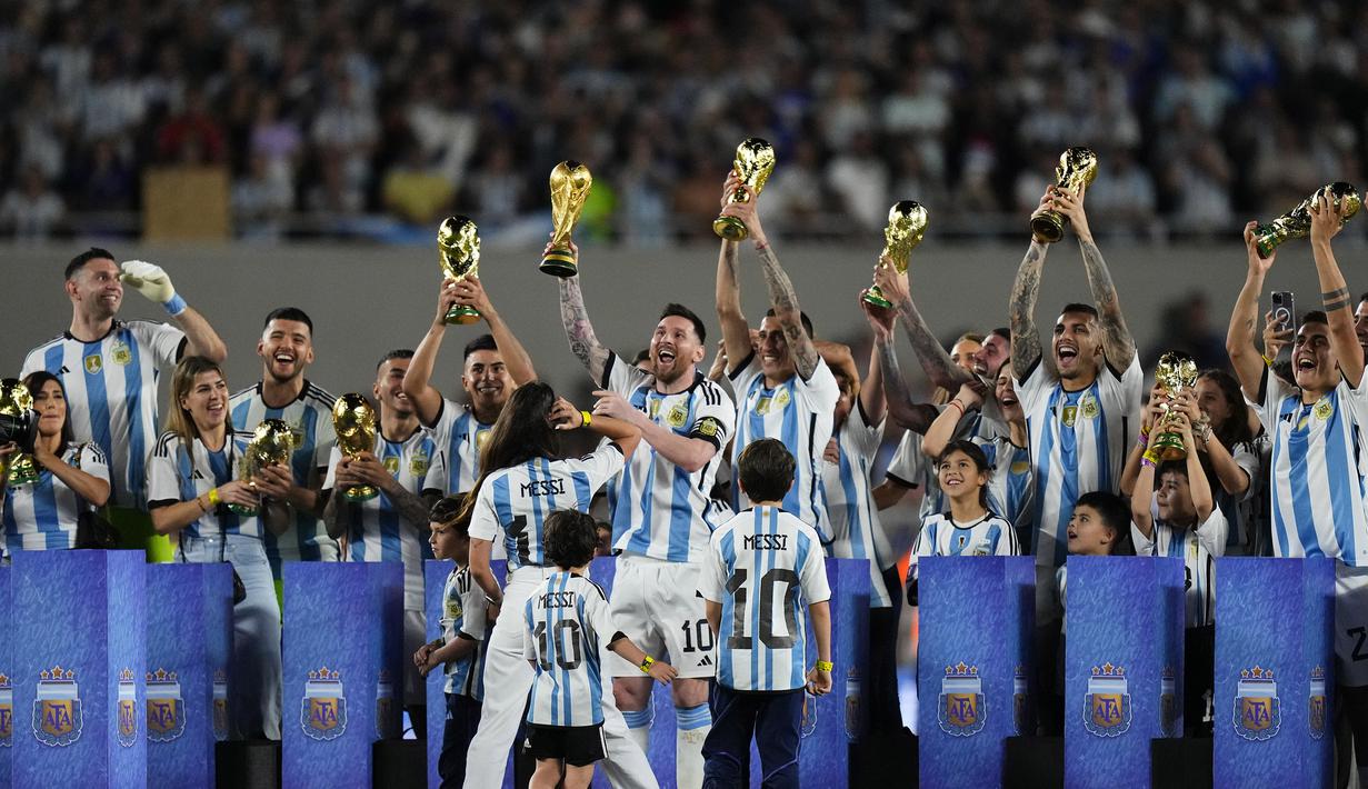 Lionel Messi memimpin momen mengangkat trofi Piala Dunia 2022 di tengah lapangan bersama seluruh penggawa La Albiceleste diikuti dengan keluarga setiap pemain yang turut hadir di lapangan. (AP Photo/Natacha Pisarenko)