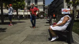 Seorang wanita melindungi kepalanya di bawah majalah di Alun-Alun Plaza del Castillo, Pamplona, Spanyol, 15 Juni 2022. Layanan cuaca Spanyol mengatakan massa udara panas dari Afrika Utara memicu gelombang panas besar pertama di negara itu tahun ini dengan suhu diperkirakan akan meningkat menjadi 43 derajat Celcius (109 derajat Fahrenheit) di area tertentu. (AP Photo/Alvaro Barrientos)