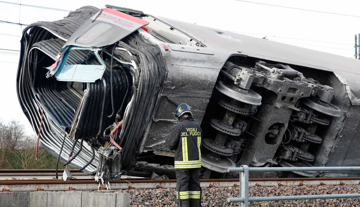 Seorang petugas pemadam kebakaran memeriksa gerbong kereta yang tergelincir, dekat Lodi, Italia utara, Kamis (6/2/2020). Kereta berkecepatan tinggi itu keluar dari rel hingga menewaskan sedikitnya dua orang dan sekitar 30 lainnya luka dalam insiden itu. (AP/Antonio Calanni)