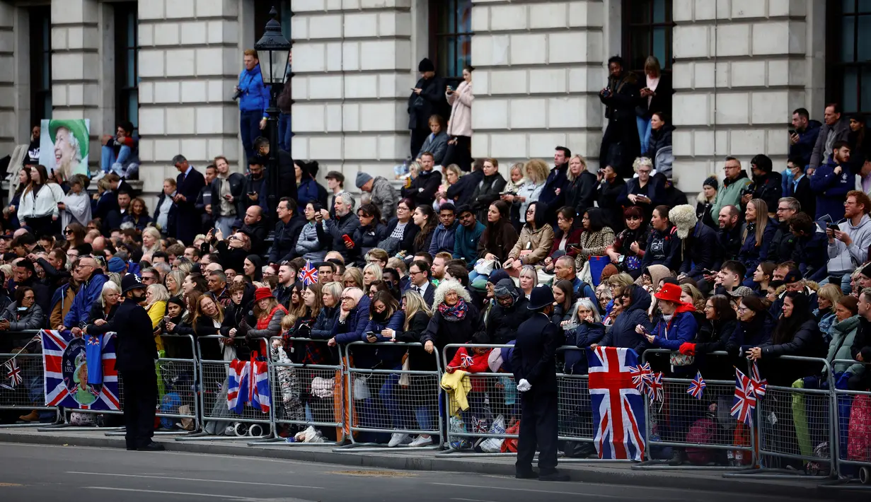 Orang-orang menunggu di sepanjang rute peti mati Ratu Elizabeth II akan ditarik dengan kereta setelah upacara pemakamannya di Westminster Abbey, London, Inggris, Senin (19/9/2022). Lebih dari 10.000 petugas polisi akan bertugas pada hari pemakaman kenegaraan Ratu Elizabeth II. (Sarah Meyssonnier/Pool Photo via AP)