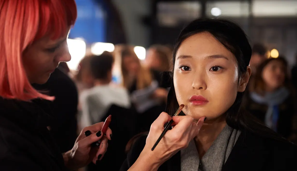 Seorang model saat dirias di belakang panggung sebelum berjalan di atas catwalk membawakan busana asal Inggris Temperley London pada Autumn / Winter 2017 London Fashion Week di London, Inggris (19/2).  (AFP Photo / Niklas Halle'n) 