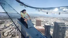 Seorang wanita mencoba berseluncur menggunakan skyslide di lantai 69 dan 70 dari Bank Tower AS, Los Angeles , California, (20/6). Tempat yang dinamakan OUE Skyspace LA ini kita dapat melihat panorama indah kota LA dari atas. (REUTERS / Lucy Nicholson)