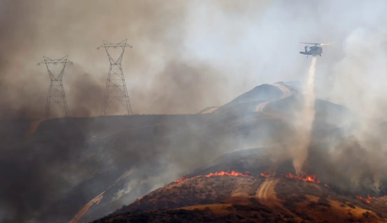 Helikopter pemadam kebakaran melakukan tetesan air saat Route Fire terbakar di dekat Castaic, California (31/8/2022). Evakuasi telah diperintahkan karena kebakaran hutan telah menghanguskan lebih dari 600 hektar dan menutup jalan bebas hambatan 5 di tengah gelombang panas di California Selatan. (Mario Tama/Getty Images/AFP)
