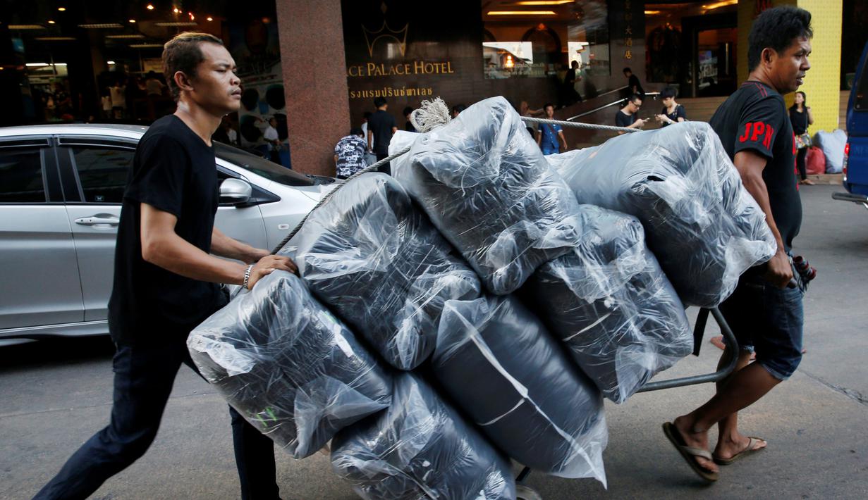 Pedagang membawa karung berisi T-shirt hitam untuk didistribusikan ke sejumlah toko untuk pembeli di Pasar Grosir Bo Bae Bangkok, Thailand (15/10). (REUTERS / Edgar Su)