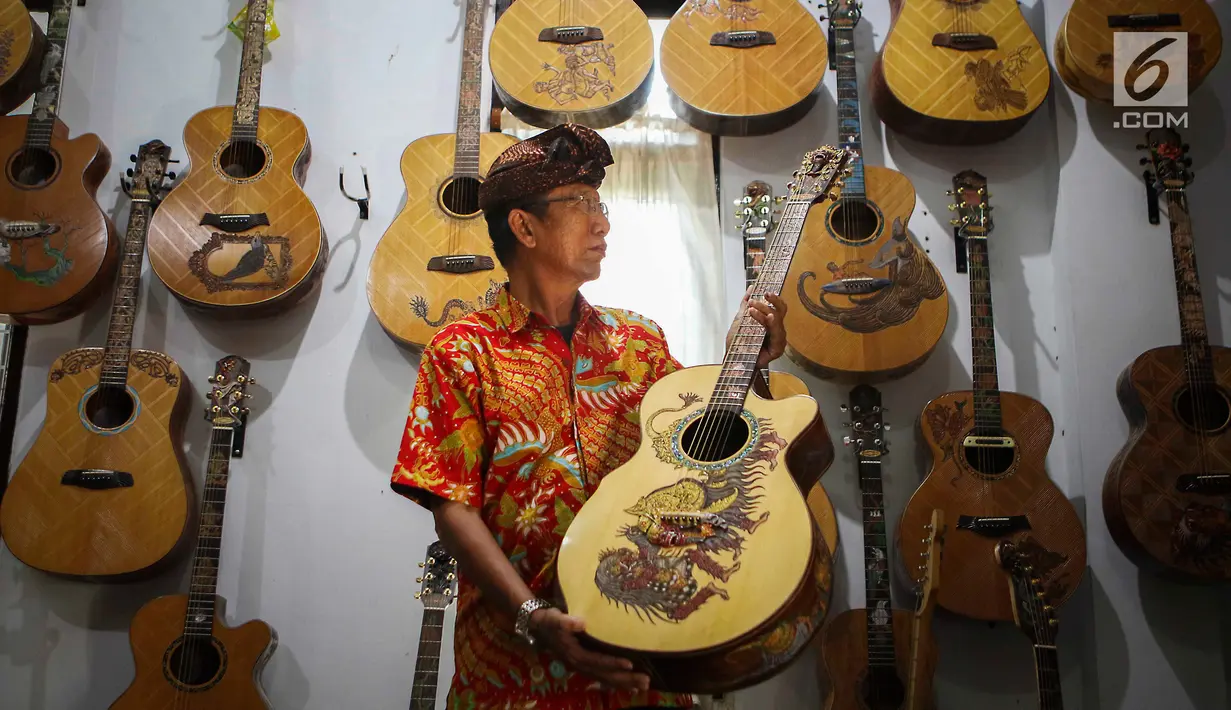 I Wayan Tuges melihat gitar yang telah diukirnya di workshop pembuatan gitar berlabel Blueberry di Jalan Baruna No. 5 Guwang, Sukowati, Bali, Senin (15/10). Gitar-gitar produksinya itu dibanderol seharga puluhan juta rupiah. (Liputan6.com/Angga Yuniar)