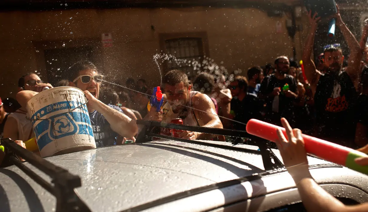 Orang-orang saling menembakan air saat mengikuti perang air tahunan di daerah Vallecas di Madrid, Spanyol (16/7). Perang air ini dinamakan Naval Battle of Vallecas. (AP Photo / Francisco Seco)