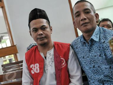 Feriyanto (kiri) berselfie saat akan mengikuti sidang perdana di Pengadilan Negeri Jakarta Selatan, (23/6). Jaksa Penuntut Umum (JPU) menilai Feriyanto telah melakukan provokasi sopir taksi se-Jabodetabek via media sosial. (Liputan6.com/Yoppy Renato)
