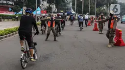Satpol PP menghentikan pesepeda yang tidak mengenakan masker dengan benar di kawasan Bundaran HI, Jakarta, Minggu (17/1/2021). Pemerintah terus melakukan berbagai upaya guna mencegah penyebaran COVID-19 dan menurunkan angka masyarakat yang terpapar virus corona. (Liputan6.com/Johan Tallo)