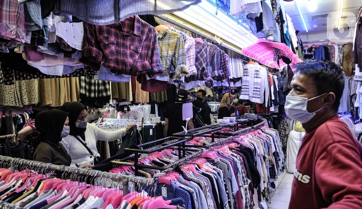 Pedagang mengamati pengunjung memilih pakaian bekas impor di Pasar Senen, Jakarta, Kamis (4/3/2021). Sepinya penjualan diperparah dengan rumor pakaian bekas impor berpotensi menyebarkan virus COVID-19. (merdeka.com/Iqbal S. Nugroho)