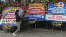 Seorang perempuan bermain ponsel di dekat  karangan bunga ucapan selamat yang berjejer di sekitar Gedung Merah Putih KPK, Jakarta, Jumat (20/12/2019). Papan karangan bunga tersebut berisi ucapan selamat terhadap dilantiknya pimpinan KPK periode 2019-2023. (merdeka.com/Imam Buhori)
