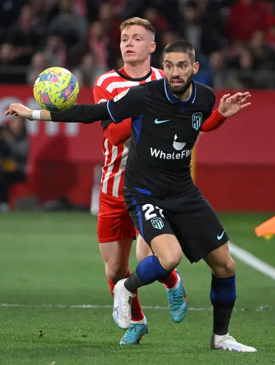 <p>Pemain Atletico Madrid Yannick Ferreira-Carrasco (kanan) bersaing memperebutkan bola dengan pemain Girona Viktor Tsygankov pada pertandingan sepak bola Liga Spanyol di Stadion Montilivi, Girona, Spanyol, 13 Maret 2023. Gol tunggal Alvaro Morata membawa Atletico Madrid mengalahkan Girona. (LLUIS GENE/AFP)</p>
