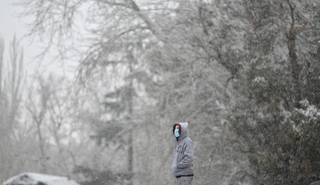 Seorang pria berdiri saat salju turun di Taman Retiro di pusat kota Madrid (7/1/2021). Wilayah timur Castilla-La Mancha, wilayah Madrid dapat melihat timbunan salju dengan total antara 20 dan 50 sentimeter. (AFP/Gabriel Bouys)