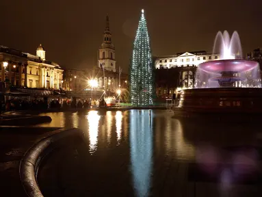 Kolam air mancur memantulkan refleksi pohon natal Norwegia setelah lampunya dinyalakan dalam upacara di Trafalgar Square, London, Kamis (6/12). Pohon cemara itu merupakan pohon natal hadiah tahunan dari kota Oslo kepada rakyat Inggris. (AP/Matt Dunham)