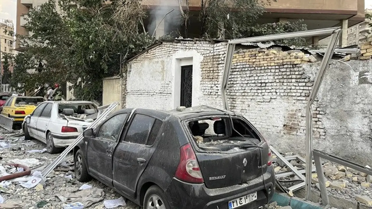 Puing-puing dari sebuah gedung apartemen terlihat di atas mobil-mobil yang diparkir setelah serangan Israel ke Teheran, Iran, Jumat, (13/6/2025).