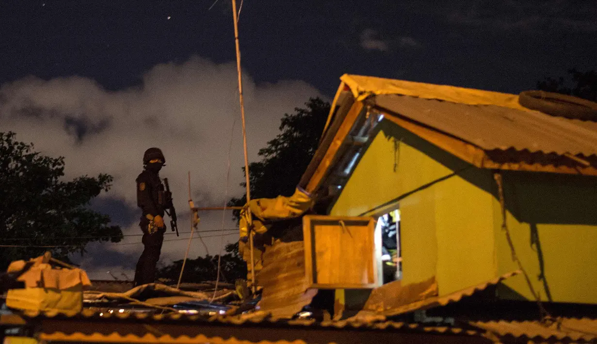 Seorang polisi terus berjaga dari atap selama penggerebekan bandar narkoba di Desa Maharlika, Taguig, selatan Manila (28/2). Penggerebekan dilakukan untuk menangkap lima pengedar narkoba, namun hanya dua yang ditangkap. (AFP Photo/Noel Celis)