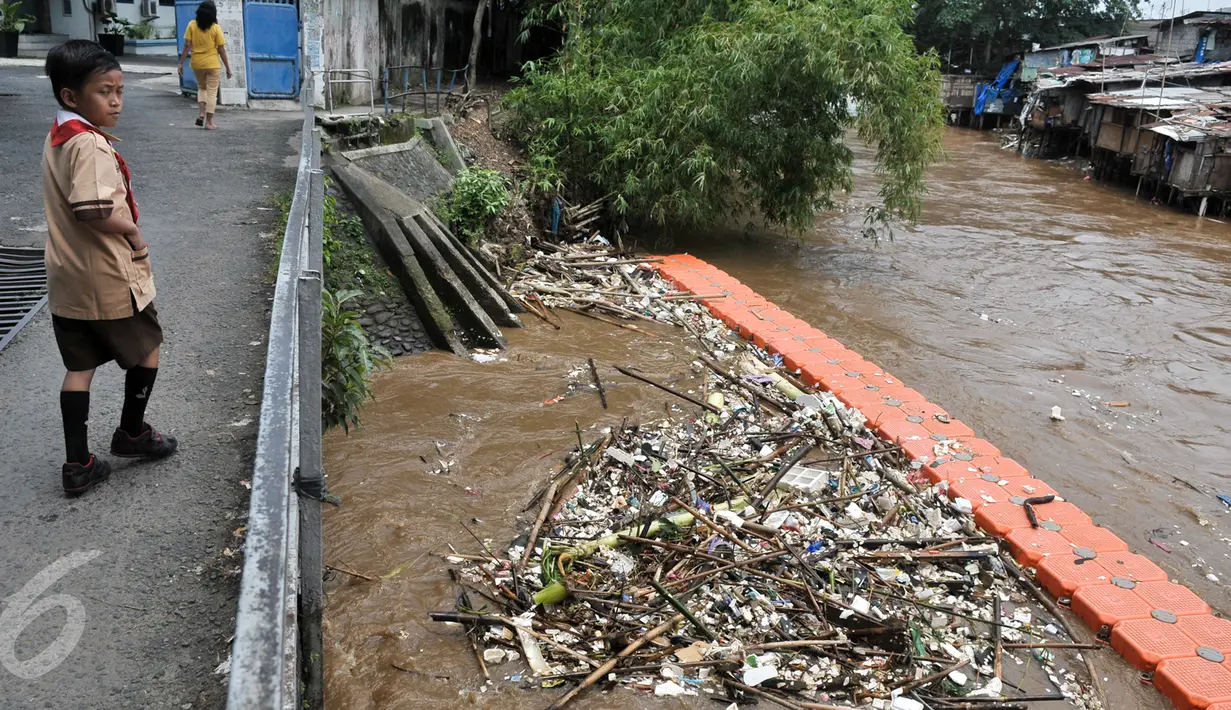 Seorang anak melintas di samping sungai Ciliwung di kawasan Manggarai, Jakarta Selatan, Rabu (8/3). Meningkatnya debit air di sungai Ciliwung dibarengi dengan sampah yang terbawa aliran sungai. (Liputan6.com/Yoppy Renato)
