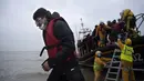 Para migran dibantu ke darat dari sekoci RNLI (Royal National Lifeboat Institution) setelah diselamatkan saat melintasi Selat Inggris di sebuah pantai di Dungeness, Inggris tenggara (24/11/2021). (AFP/Ben Stansall)