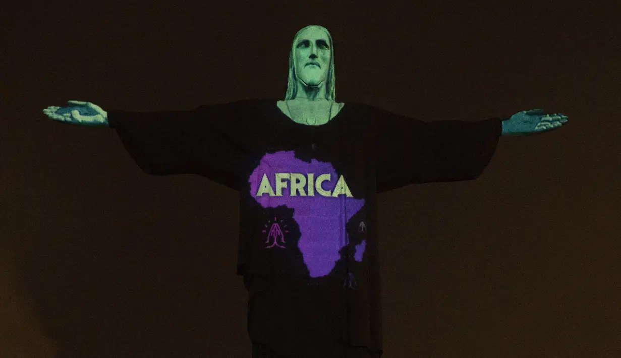 Patung Christ the Redeemer bermandi cahaya dengan peta dan kata ‘Africa’ di Rio de Janeiro, Brasil, Rabu (18/3/2020). Pertunjukan ini untuk menunjukkan dukungan bagi mereka yang menderita virus corona COVID-19. (AP Photo/Silvia Izquierdo)