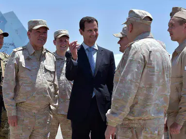 Presiden Suriah Bashar al-Assad berbincang dengan pasukan Rusia saat mengunjungi pangkalan udara Rusia di Khmeimim, Selasa (27/6). Kunjungan ini merupakan yang pertama kalinya Assad lakukan ke pangkalan. (Syrian Presidency via Facebook)