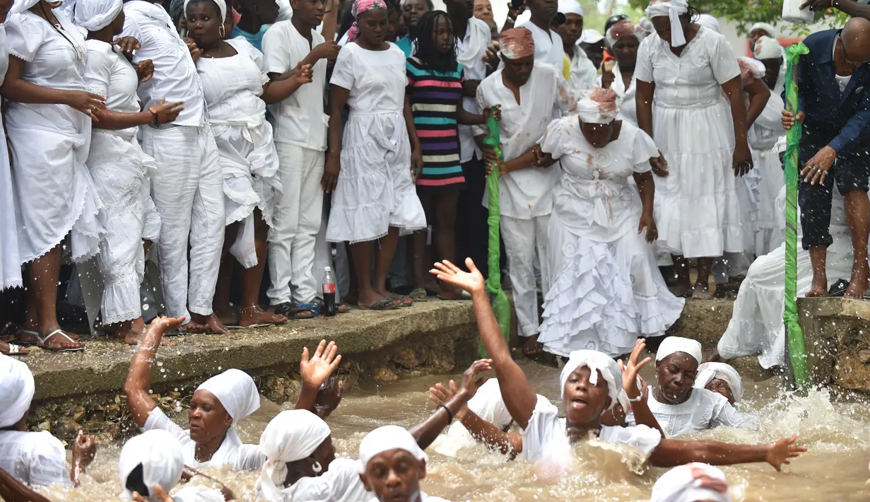 Sejumlah pengikuti Voodoo Haiti melakukan ritual saat mandi di kolam suci selama upacara voodoo di Souvenance, Haiti (4/1). Mereka datang ke Souvenance pada akhir pekan Paskah untuk memberikan penghormatan kepada para roh. (AFP/Hector Retamal)
